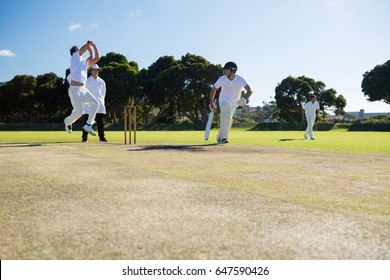 Players Playing Cricket Match At Field On Sunny Day