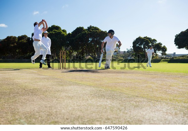 Players\
playing cricket match at field on sunny\
day