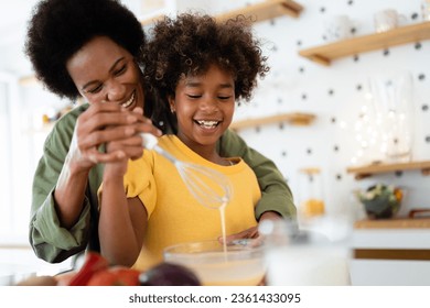 Playful African American family preparing food with wire whisk at home. - Powered by Shutterstock