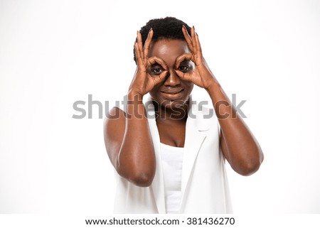 Playful african american young woman imitating glasses with hands over white background