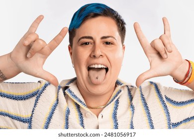 Playful androgynous person with blue hair sticking out tongue showing piercing - LGBT pride bracelet, joyful expression, fun and vibrant - inclusive and colorful. - Powered by Shutterstock