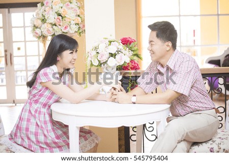 playful asian couple sits in a cute white living room
