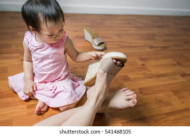 Playful Asian toddler girl having fun with her mom's shoes - Powered by Shutterstock