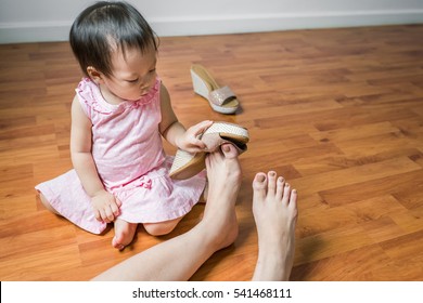 Playful Asian toddler girl having fun with her mom's shoes - Powered by Shutterstock