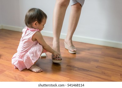 Playful Asian toddler girl having fun with her mom's shoes - Powered by Shutterstock