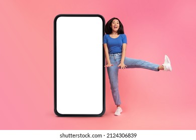 Playful asian woman jumping and having fun near huge smartphone with blank screen for mobile offer or app advertisement on pink background, mockup - Shutterstock ID 2124306839
