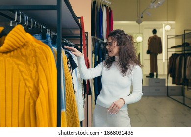 Playful attractive Female customer chooses new clothes, admiring herself in front of a mirror in a stylish boutique of shopping mall - Shutterstock ID 1868031436