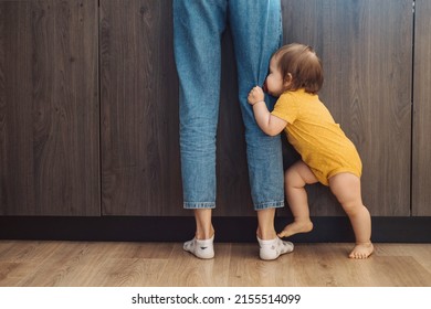 Playful baby hiding his face behind his mother's feet. Family protection.