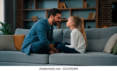 Playful Caucasian Young Family Daddy And Small Daughter Sitting Comfortable On Couch Loving Cute Girl Touching Father Nose Funny Joke Playing Game With Parent Having Fun Spending Free Time Together