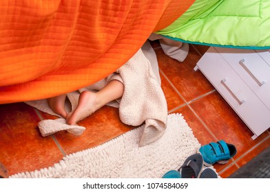 Playful Child With Bathrobe Is Hiding Under The Bed At Home