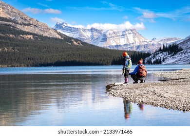 Playful children sitting at a lakeside preparing to skip rocks near Banff Canada in the Rocky Mountains of North America