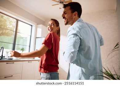 Playful couple dancing and singing in the kitchen. - Powered by Shutterstock