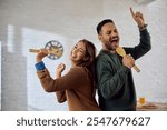 Playful couple singing and having fun while cooking in the kitchen. 