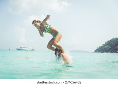 Playful Couple In The Water. Woman Jumping In The Water From The Man Shoulders. Concept About Vacations, Fun And People