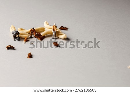 a playful and creative conceptual image featuring tiny miniature people figures working on uncooked pasta