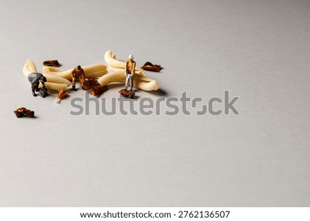 a playful and creative conceptual image featuring tiny miniature people figures working on uncooked pasta