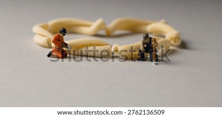a playful and creative conceptual image featuring tiny miniature people figures working on uncooked pasta