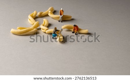 a playful and creative conceptual image featuring tiny miniature people figures working on uncooked pasta