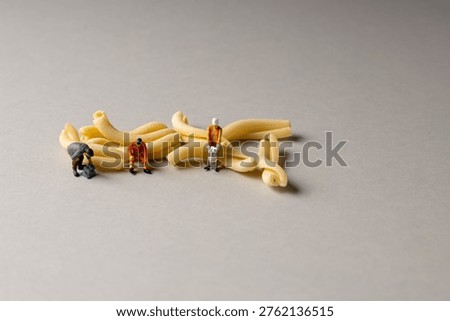 a playful and creative conceptual image featuring tiny miniature people figures working on uncooked pasta