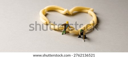 a playful and creative conceptual image featuring tiny miniature people figures working on uncooked pasta