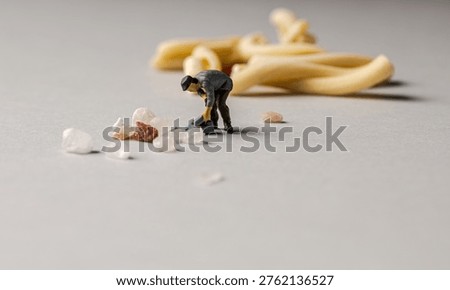 a playful and creative conceptual image featuring tiny miniature people figures working on uncooked pasta