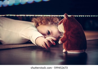 Playful Cute Curious Baby Pulling Hand To Toy Under The Bed In Vintage Style 