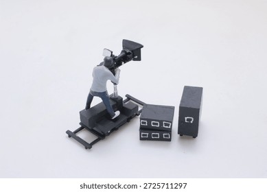 playful diorama of tiny figures making a movie: a cameraman on a dolly, a