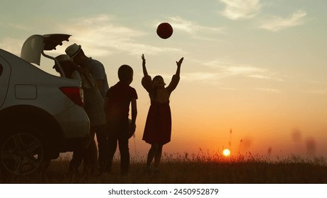 Playful family at sunset by car. cheerful children parents going on travel road trip by automobile packing baggage putting luggage in trunk kids playing ball. Packing preparation for family picnic. - Powered by Shutterstock