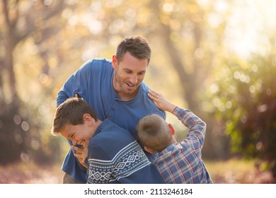 Playful Father And Sons Rough Housing Outdoors