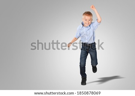 Playful frolic kid boy stands and posing over gray background
