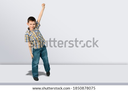 Playful frolic kid boy stands and posing over gray background