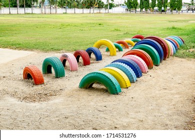 playful and fun concept pf colorful sets of tire playground fun activity for children kids playful happy and enjoy playing with friends at school yard in sand pit next to green grass field background