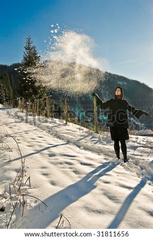 Playful girl in a snow-covered mountainscape.