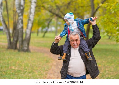 Playful Grandfather Spending Time With His Grandson In Park On Sunny Day