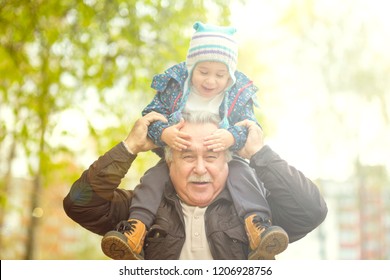 Playful Grandfather Spending Time With His Grandson In Park On Sunny Day