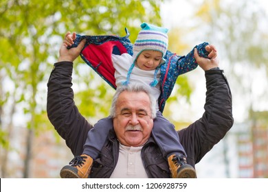 Playful Grandfather Spending Time With His Grandson In Park On Sunny Day