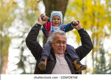 Playful Grandfather Spending Time With His Grandson In Park On Sunny Day