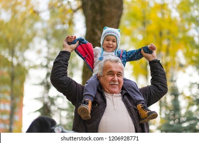 Playful Grandfather Spending Time With His Grandson In Park On Sunny Day