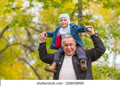 Playful Grandfather Spending Time With His Grandson In Park On Sunny Day