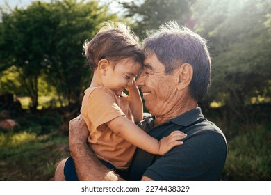 Playful grandfather spending time with his grandson in park on sunny day