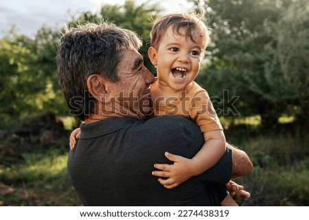 Playful grandfather spending time with his grandson in park on sunny day