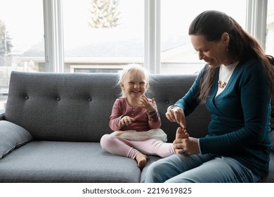 Playful grandmother tickling granddaughter s toes on living room sofa - Shutterstock ID 2219619825