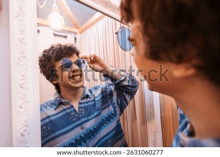 A Playful Guy Trying on Different Sunglasses in Front of a FullLength Mirror