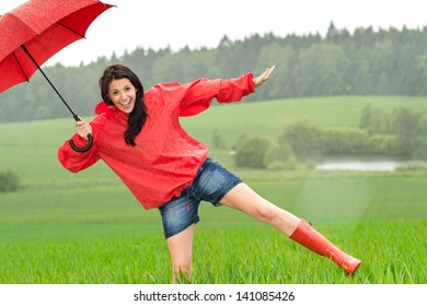 Playful happy girl in the rain with red umbrella