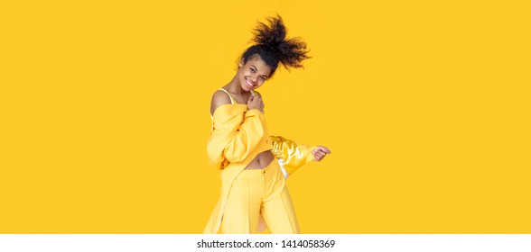 Playful Happy Young African Woman Wear Stylish Yellow Clothes Look At Camera Dancing Funky Black Teen Fashion Girl On Summer Studio Background, Horizontal Banner Header Website Design, Copy Space