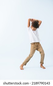 Playful Indian Boy Makes Hard Blow With An Imaginary Sword Or A Hammer Against Bluish White Background. He Is Wearing White T Shirt. Eyes Closed.