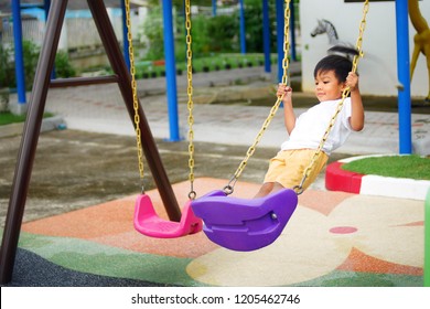 Playful kid concept, A child boy standing on the purple swing seat in the playground. He very happy and smiling every time. - Shutterstock ID 1205462746