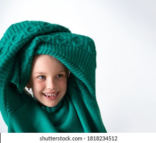 Playful Little Girl Wearing Knitted Green Sweater That Is Too Big For Her And Raising Hands In Long Sleeves Above Head. Happy Childhood, Facial Expression, Cute Kids. Close Up Shot Isolated On White.