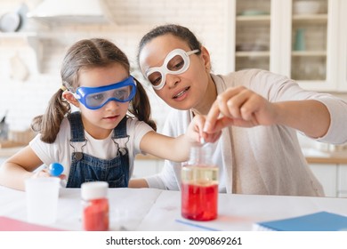 Playful mother and little daughter girl in protective wear having fun playing with chemistry lab game together. Scientific tests experiments at home for school project homework. - Powered by Shutterstock