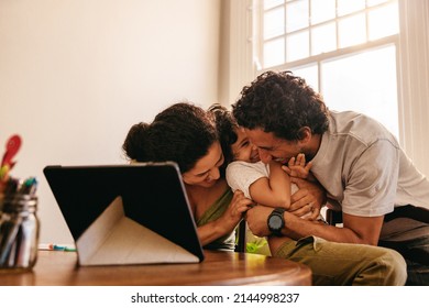 Playful parents tickling their son indoors at home. Family of three laughing and having a good time together. Mom and dad spending quality time with their son on the weekend.